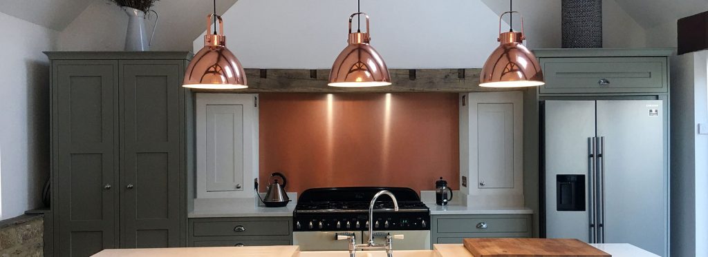 copper splashback in a traditional sage coloured kitchen with high sealing. 