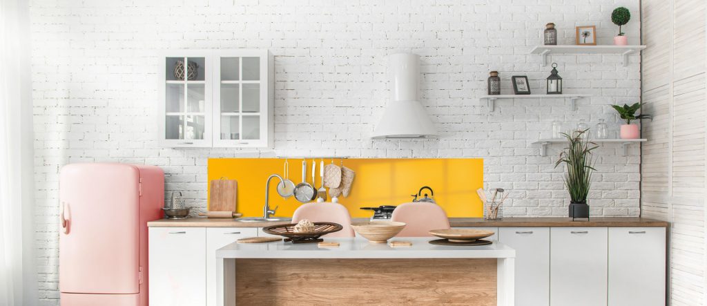 White kitchen with orange splashback and pink fridge.