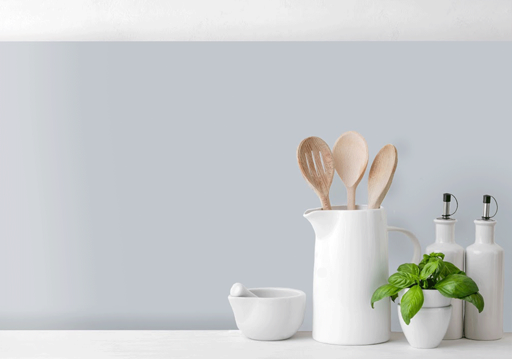 Soft grey glass splashback in a bright contemporary kitchen featuring minimalist styling, neutral décor, white accessories, and a clean modern worktop design.